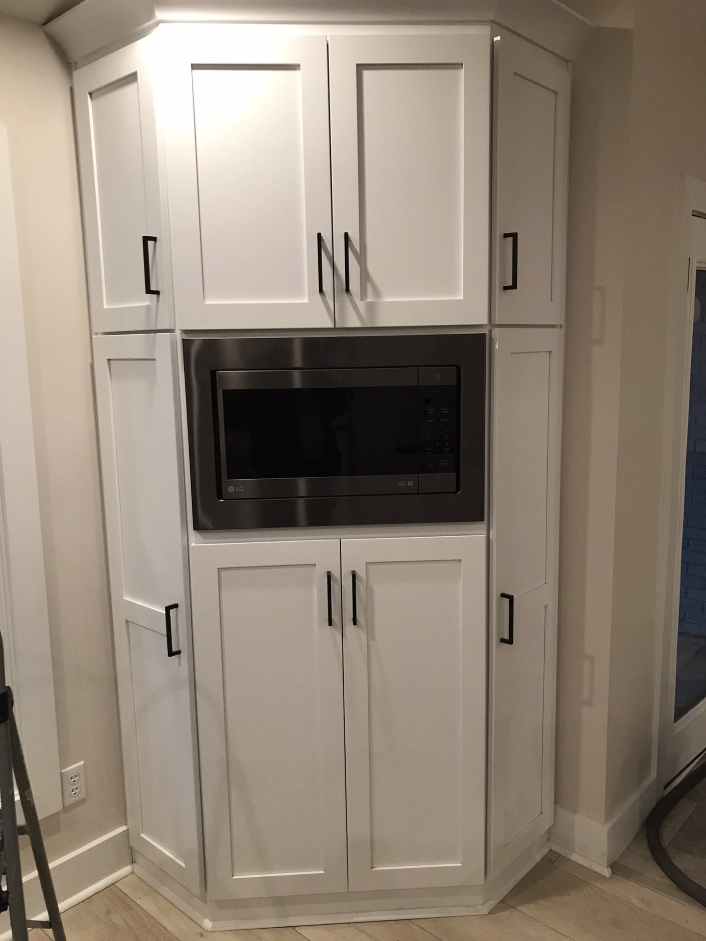 Custom white pantry cabinetry surrounding a built-in microwave
